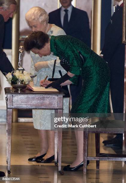 Queen Elizabeth II and Princess Anne, Princess Royal sign the visitors book after a reception to mark the Centenary of the Women's Royal Navy Service...