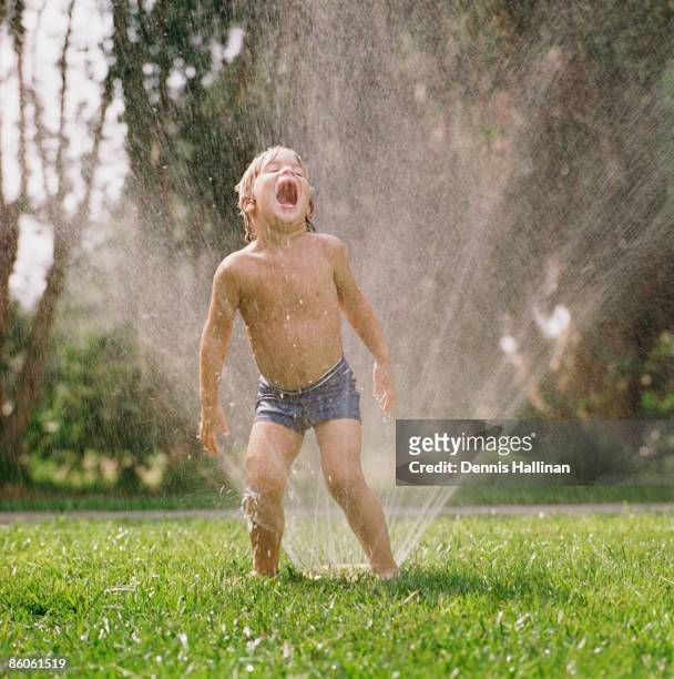 Boy playing outside with sprinkler
