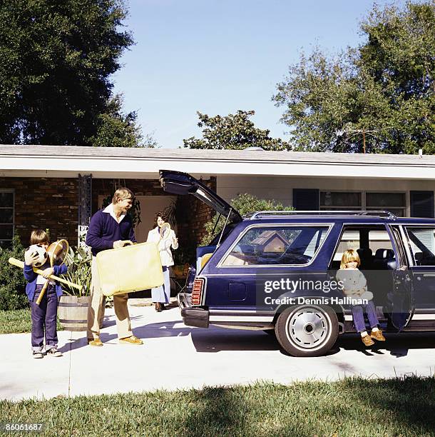 family going on vacation loading station wagon - vintage car stockfoto's en -beelden