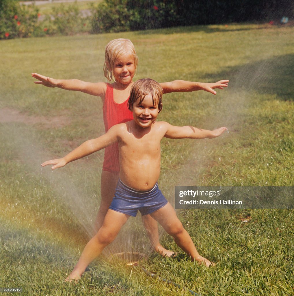 Children playing with sprinkler in backyard