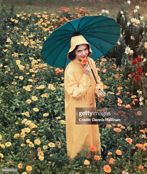 Smiling woman holding umbrella in field of flowers