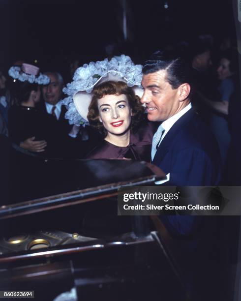 Married American actors Joan Crawford and Phillip Terry dance beside a piano at an uspecified event, mid to late 1940s.