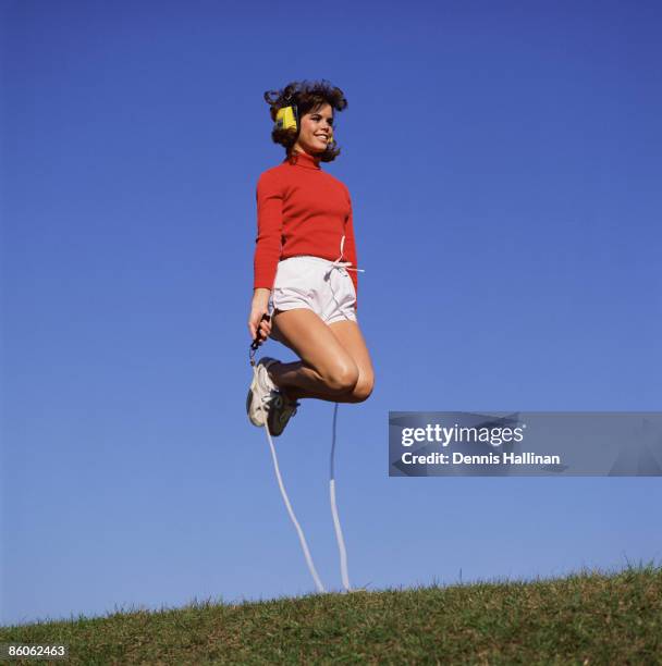 Woman exercising with jump rope while listening to headset radio.