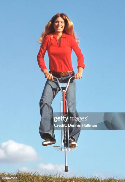 Happy woman jumping using pogo stick