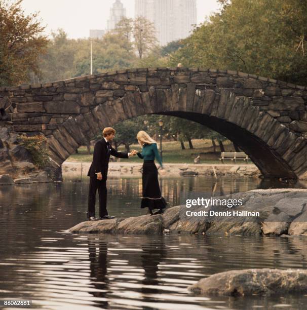 Couple standing on lakeshore near stone bridge