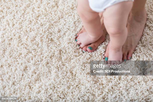 baby wandelingen op mama's voeten - tapijt stockfoto's en -beelden