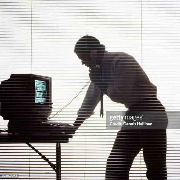 Silhouette of businessman talking on phone using computer