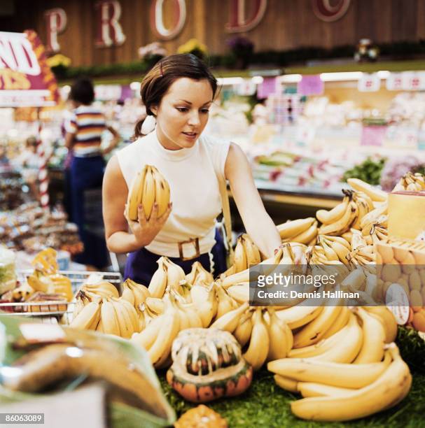 Woman buying fresh bananas at grocery store