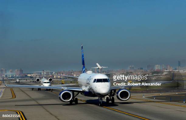 JetBlue passenger jet and other departing aircraft taxi toward the runway at LaGuardia Airport in New York, New York.