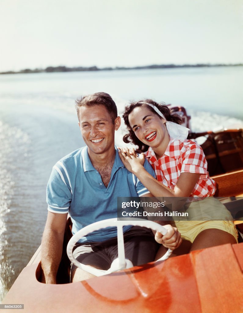 Smiling retro couple enjoying a speed boat ride
