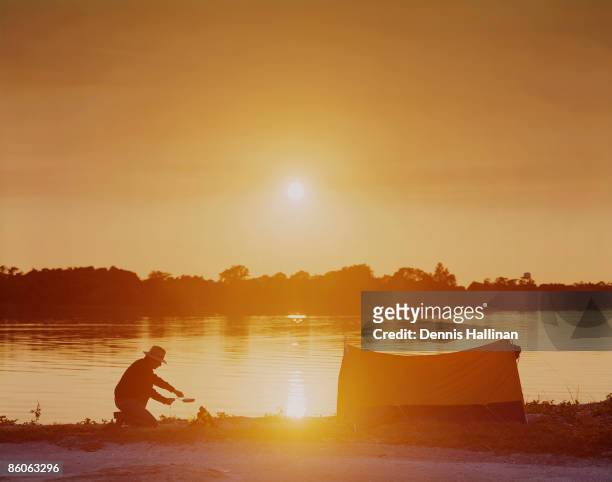 Man preparing food on campsite at sunset