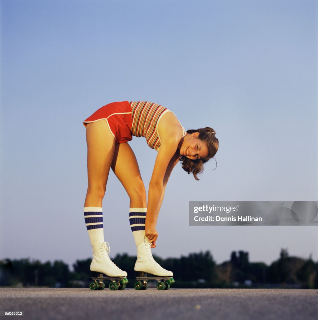 Smiling woman tying laces of roller skates