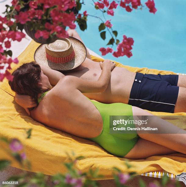 Couple relaxing on lounge chairs by swimming pool