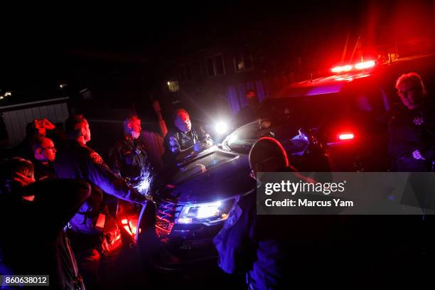 California Highway Patrol officers gather around Sergeant Rivers, center, as they study the neighborhood maps so that they can go door to door to...