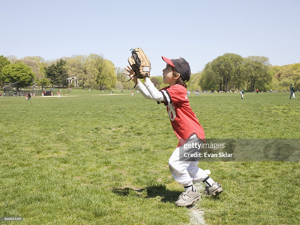 Side view of boy catching baseball in glove