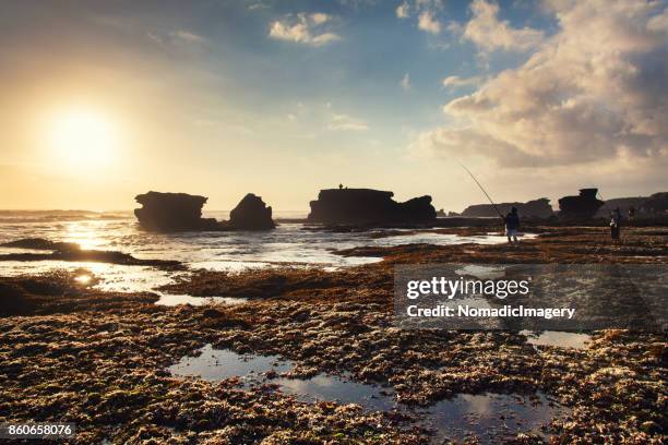 twilight sunset creates silhouettes of sea stacks at a bali beach - stack of sun lounges stock pictures, royalty-free photos & images