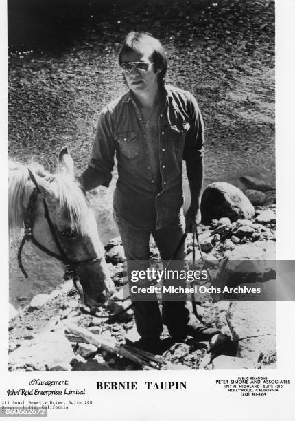 Songwriter Bernie Taupin poses for a portrait with a horse in November 1974.