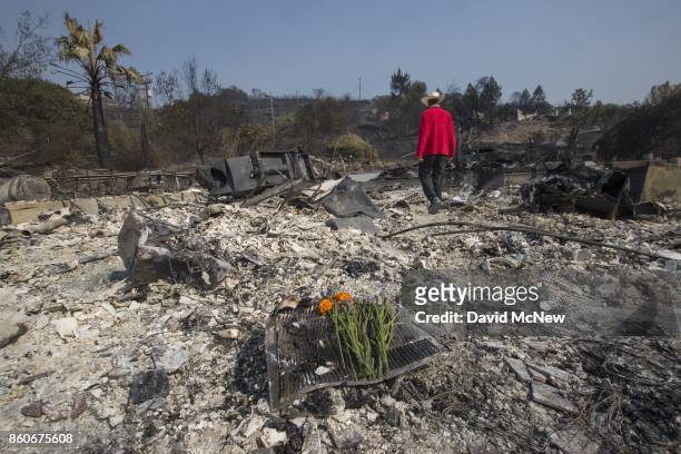 Flowers mark the spot where his father died as Mike Rippey walks through the ruins of the house of 100-year-old Charles and 98-year-old Sara Rippey,...