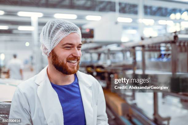 joven científico sonriente posando en la fábrica moderna - planta-de-procesamiento-de-comida fotografías e imágenes de stock