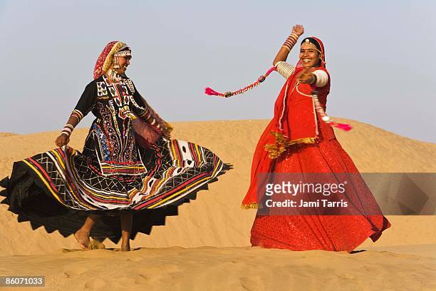 women in saris dancing in sand - rajasthani women stock-fotos und bilder