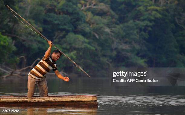 Fisherman Edmilson Ferreira throws a harpoon into the water as he fishes for arapaima, also known as pirarucu in the Western Amazon region near Volta...