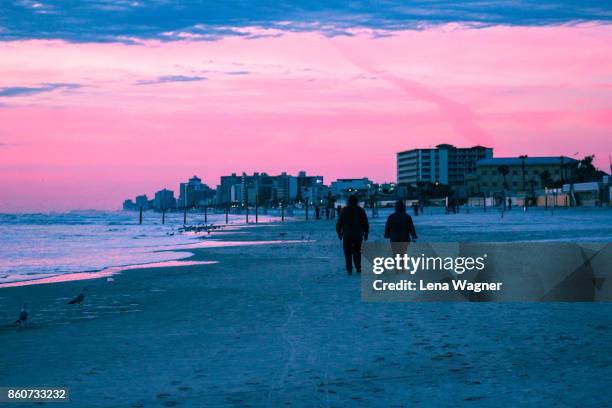 couple walking away on beach during sunrise - daytona beach 個照片及圖片檔