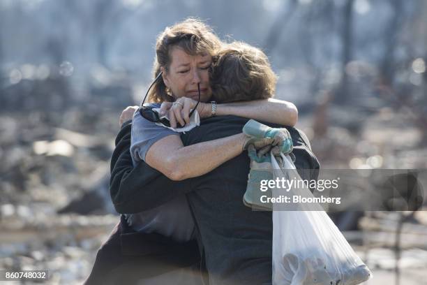 Residents embrace as they look through their burned home in Santa Rosa, California, U.S., on Thursday, Oct. 12, 2017. Wildfires that tore through...