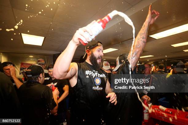 Jake Arrieta of the Chicago Cubs celebrates in the clubhouse with teammates after defeating the Washington Nationals 9-8 in game five of the National...