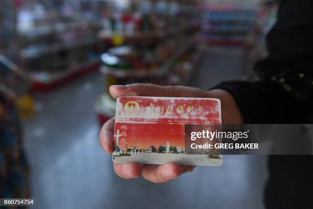 This photo taken on September 29, 2017 shows a woman displaying a "Nanjie Village Welfare Card" she uses for shopping in Nanjie village, in China's...