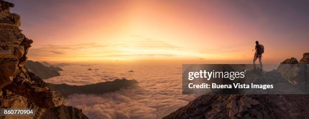 lone climber on a mountain top at dawn - on top of clouds stock pictures, royalty-free photos & images