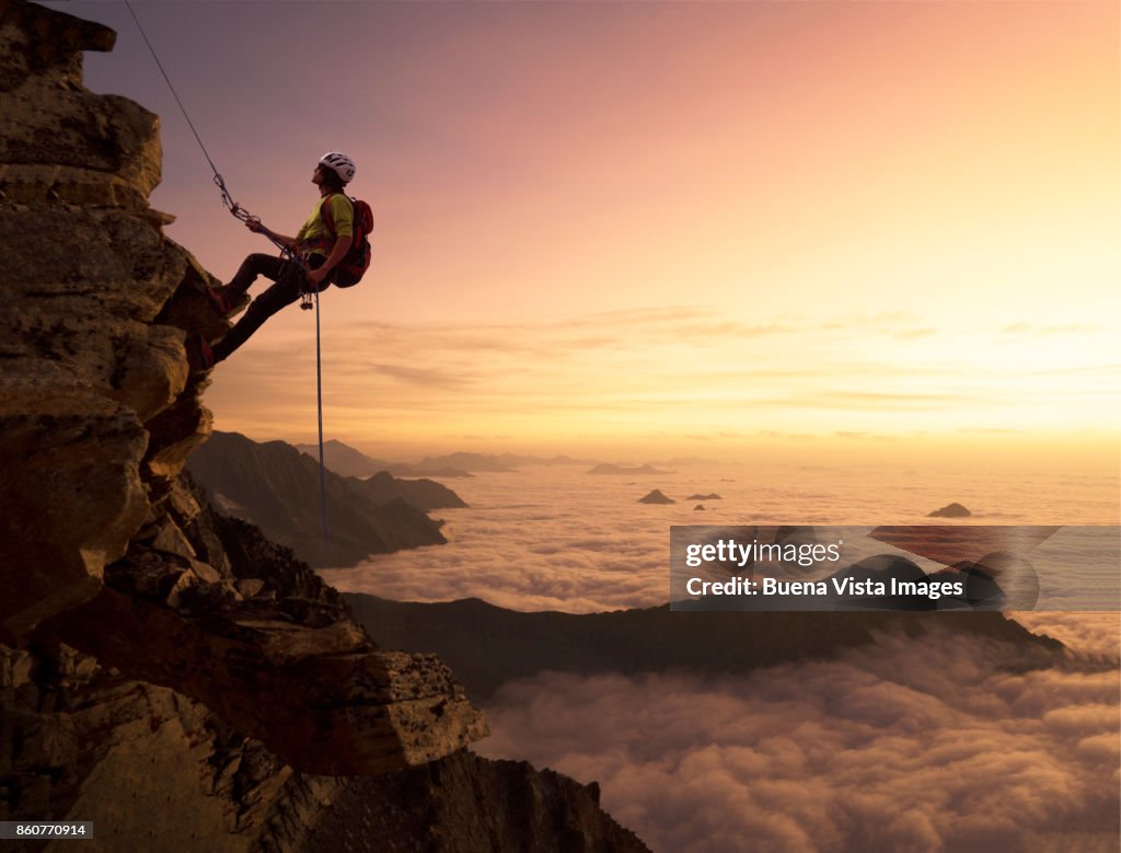 Climber on a rocky wall over clouds