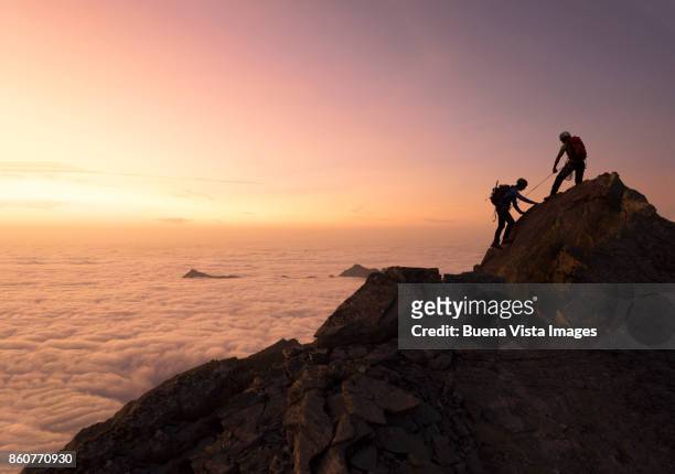 climbers reaching a mountain top. - mountaineering fotografías e imágenes de stock