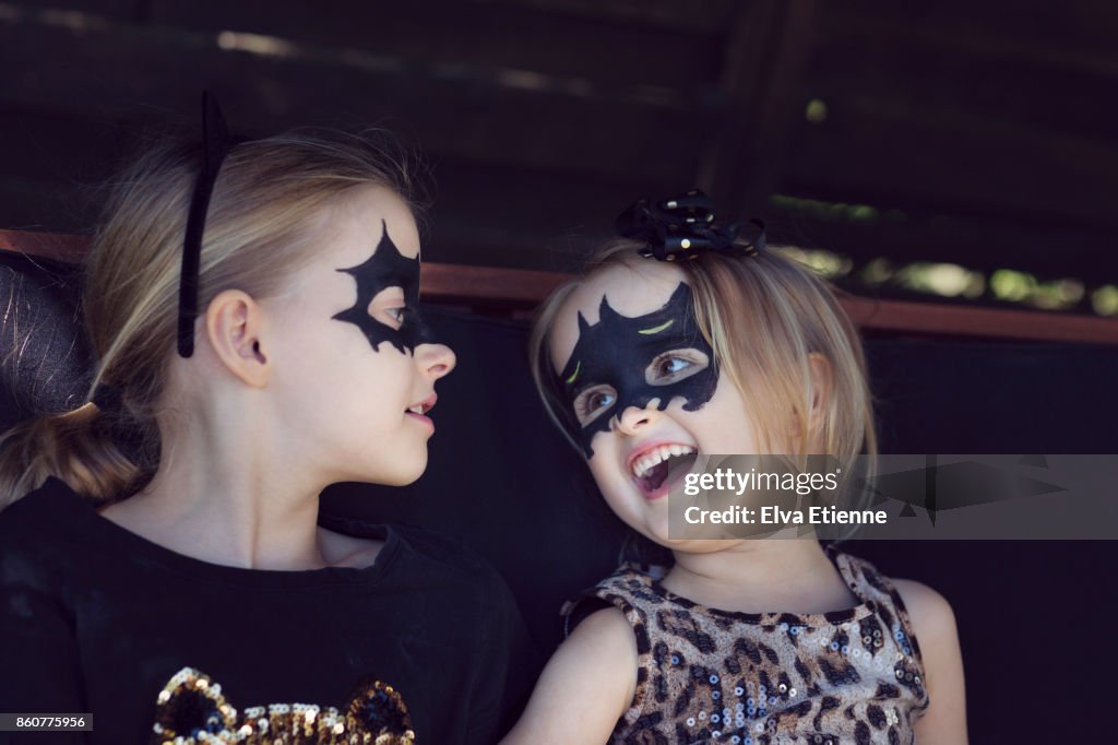 Two happy, laughing children with bat shaped face paints