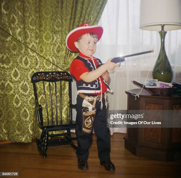 boy dressed as cowboy aiming toy gun - toy gun stock pictures, royalty-free photos & images