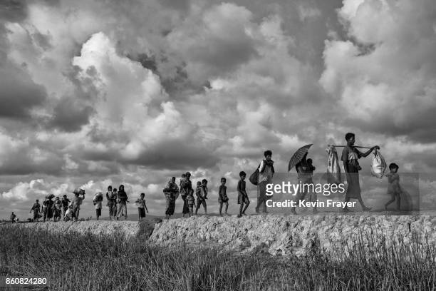 Rohingya refugees carry their belongings as they walk on the Bangladesh side of the Naf River after fleeing Myanmar, on October 2, 2017 in Cox's...