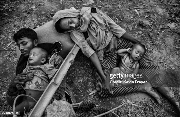 Rohingya refugees Minara Hassan and her husband Ekramul lay exhausted on the ground on Bangladesh side of the Naf River after fleeing their home in...