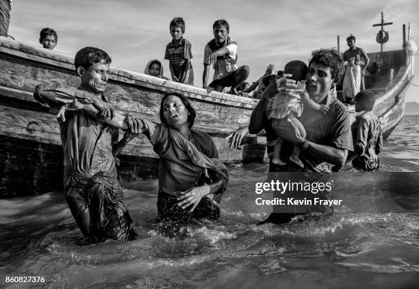 Shikira Arifullah, a 22-year-old Rohingya refugee woman from Guddumpara village, is helped from a boat as she arrives exhausted on the Bangladesh...
