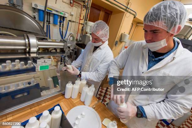 Employees manufacturing cosmetics products use a closing and filling machine at the Saint-Vincent abbey in Chantelle on September 30, 2017. Sisters...