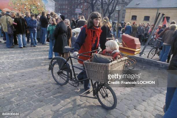 Une femme et son enfant à vélo dans le quartier de Christiania autoproclamé ville libre et communauté autogérée en mars 1976 à Copenhague, Danemark.