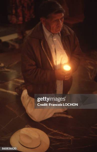 Homme agenouillé tenant une bougie pendant une cérémonie religieuse en janvier 1979, Mexique.