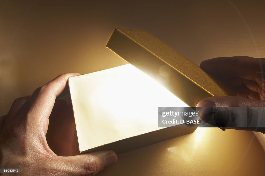 Man opening a box with light coming out.