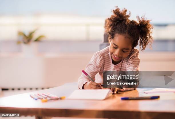 linda chica negro relajante en casa y dibujando en un papel. - kid with markers fotografías e imágenes de stock