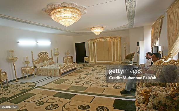 Iraqis stand inside a marbled room, where Saddam supposedly once slept, at one of the former dictator 's palace villas, which can be rented for about...