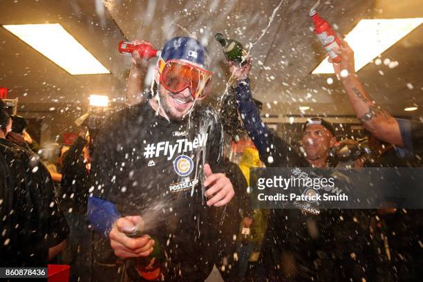 Kris Bryant of the Chicago Cubs celebrates in the clubhouse with teammates after defeating the Washington Nationals 9-8 in game five of the National...