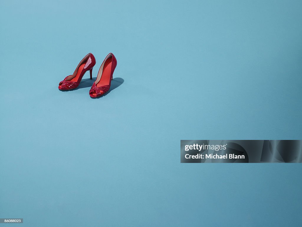 Red shoes sit on a blue backdrop