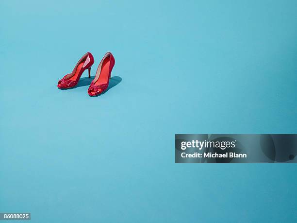 red shoes sit on a blue backdrop - red shoe stockfoto's en -beelden