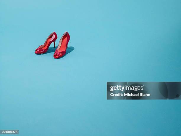 red shoes sit on a blue backdrop - high heel stock pictures, royalty-free photos & images