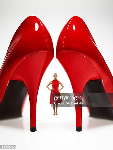 woman looking at large red heels - red shoe stock-fotos und bilder