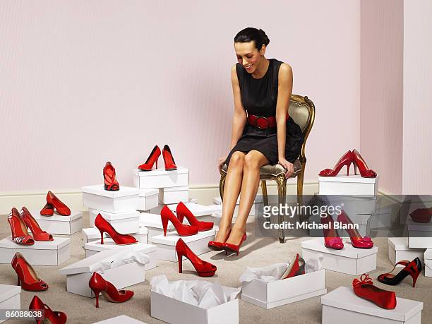 woman sits with red shoes surrounding her - dress shoe - fotografias e filmes do acervo
