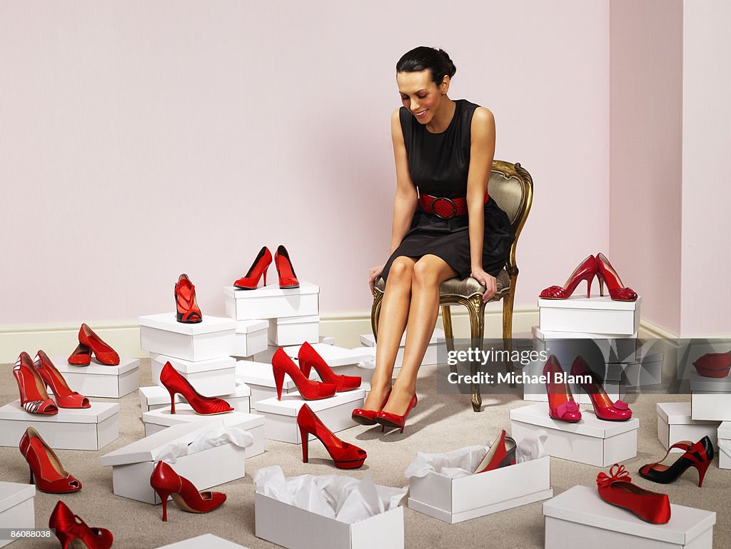 Woman sits with red shoes surrounding her